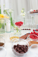 Raspberry berry in transparent cup is on table. Light snacks on festive table.Sweet chocolate paste. Copy space. Vertical photo.