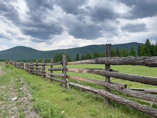 Fototapeta na wymiar Wooden fence on the background of mountains in the Altai Republic