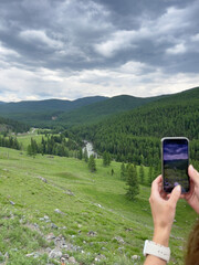 Taking a photo of the landscape with a smartphone in the mountains.