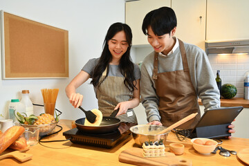 Married young couple in love having fun cooking together in kitchen, spending leisure weekend at home