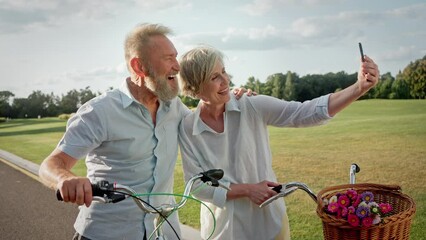 Affectionate couple with bikes taking selfie on smartphone