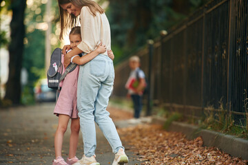 Fototapeta premium Boy is standing at background. Woman with two kids are going to school, conception of education