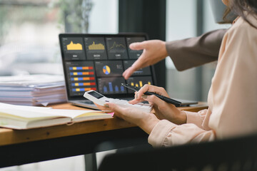 Businesswoman advisor team are analyzing data charts, graphs, and a dashboard on a laptop screen in order to prepare a statistical report and discuss financial data in an office.