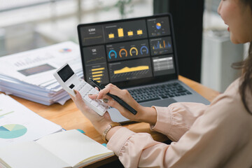 Businesswoman advisor team are analyzing data charts, graphs, and a dashboard on a laptop screen in order to prepare a statistical report and discuss financial data in an office.