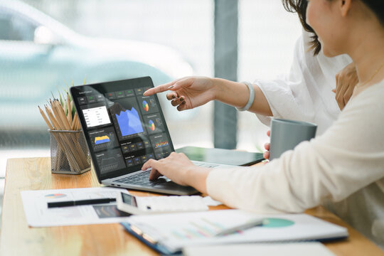 Businesswoman advisor team are analyzing data charts, graphs, and a dashboard on a laptop screen in order to prepare a statistical report and discuss financial data in an office. - Powered by Adobe