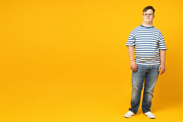 Naklejka premium Smiling young man with down syndrome in glasses posing on orange background, place for text
