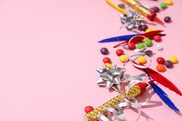 Candies, feathers and serpentine on pink background, space for text
