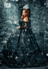 Portrait of magnificent Fashion gothic girl  .Fantasy art work.Amazing red haired model in black dress looking at camera and posing.Fairytale about young princess in snow 