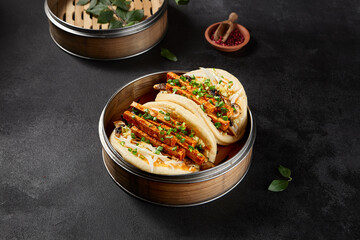 Side view of bao buns with tofu and vegetables in a steamer on a black background
