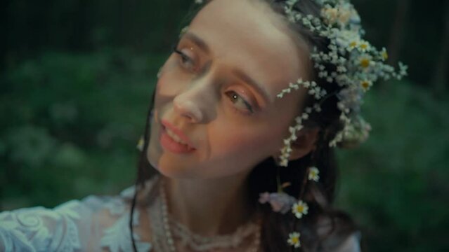 Attractive Dryad Or Forest Fairy In Flower Wreath Conjuring In Forest. A charming girl in a transparent dress walks in the forest. Mavka Naiad Forest Nymph In A Fairy Tale