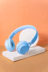 Sky blue wireless headphones on orange and brown background, minimalist photo.
