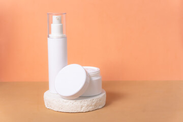 Vertical image, facial care treatment for hydration. White pots on orange and brown background.