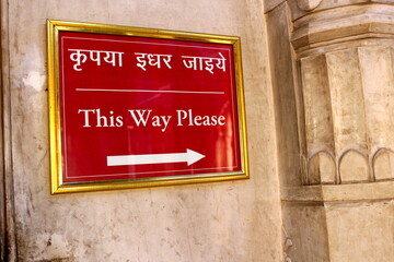 Sign board in red saying this way please