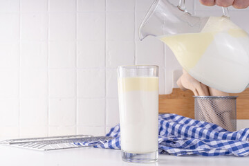 Non-Homogenized, whole milk, cream-top layered dairy product, Creamline Milk concept. Organic farm natural, unpasteurized milk in glass and jug, on white kitchen table copy space