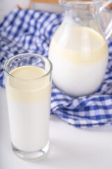 Non-Homogenized, whole milk, cream-top layered dairy product, Creamline Milk concept. Organic farm natural, unpasteurized milk in glass and jug, on white kitchen table copy space