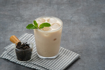 Milk tea with brown sugar syrup in a tall glass with ice and mint leaf
