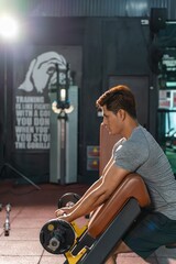 Asian man is fully dedicated to his seated bench press weight lifting exercise, emphasizing his commitment to strength training in the gym