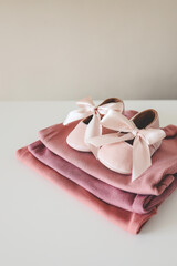 Stack of pink bodysuits and cute slippers with a bow on a white background