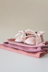 Stack of pink bodysuits and cute slippers with a bow on a white background