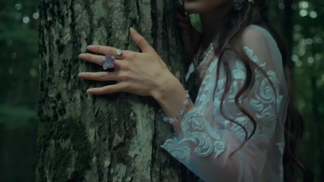 Attractive Dryad Or Forest Fairy With Flowers In Her Hair. Charming girl in a transparent white dress in the forest. Mavka Naiad Forest Nymph In A Fairy Tale
