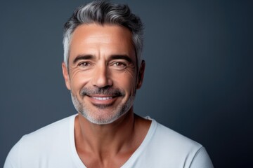 Portrait of a happily groomed fifty year old spanish man against a dark background.