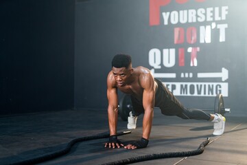 Well-built and muscular, a resilient Black man dominates battle ropes, showcasing exceptional...