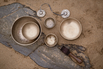 Top view of Tibetan bowls and cymbals on sand