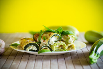 cooked zucchini rolls with cheese filling inside, in a plate