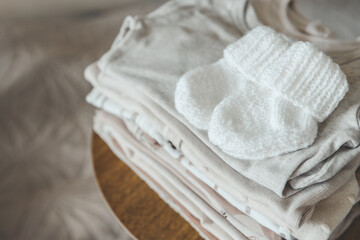 A stack of baby clothes and knitted socks for a baby