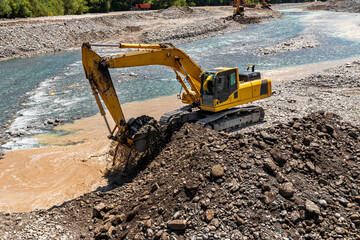 The excavator is working on expanding the riverbed. The work of heavy machinery. A yellow excavator...