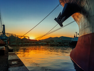 Sunset at the port. The bow of the ship in the sea against the background of the sunset sky.
