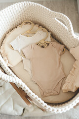 Fototapeta na wymiar Two neutral bodysuits in a baby cradle, baby clothes