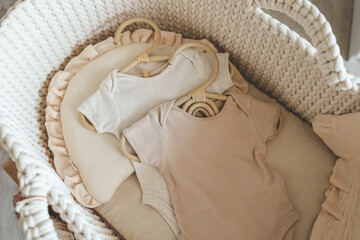 Two neutral bodysuits in a baby cradle, baby clothes