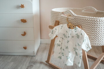 Fototapeta na wymiar Dress for a newborn girl on a wooden hanger in the nursery