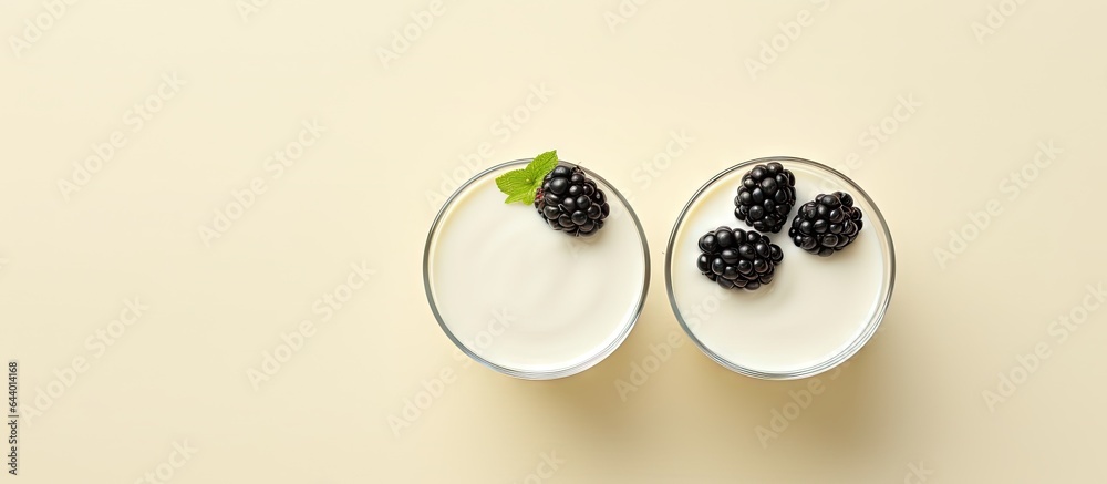 Poster front view of macro shot of wild berry topped white yogurt in two glasses on a isolated pastel backg