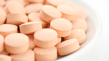 Orange pills vitamin C in white plate