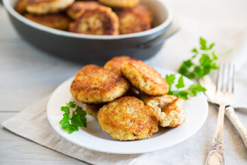Cooked fried fish cutlets in a plate with herbs.