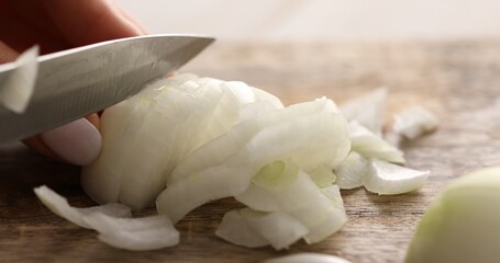 Onions are cut on a cutting board. Women's hands chop onions with a knife. Cooking food with vegetables. Close-up.