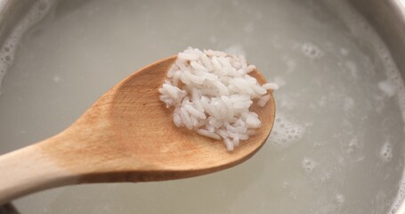 Cooking rice. A wooden spoon stirs the rice in boiling water. Food preparation. A series of photos to visualize the recipe.