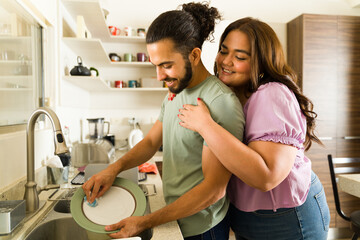 Couple in love enjoying doing housework together and doing the dishes