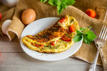 Stuffed omelette with tomatoes on a light wooden background.