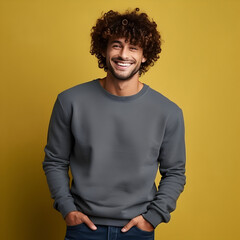 Obraz na płótnie Canvas Curly haired smiling handsome man, in gray sweater mock up at studio with yellow background