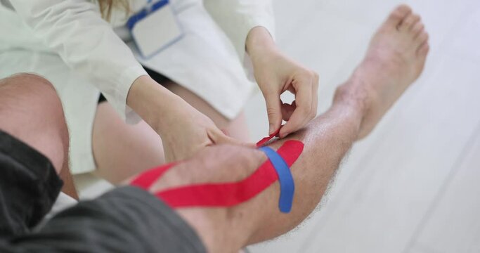 Physical therapist applies kinesio tape to patient knee. Meniscus injury in athlete