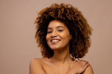 Happy biracial woman with dark curly hair, smiling with hand on shoulder