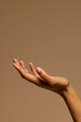 Upturned hand of biracial woman on brown background with copy space