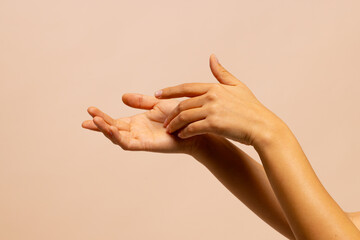 Touching hands of asian woman on pink beige background with copy space