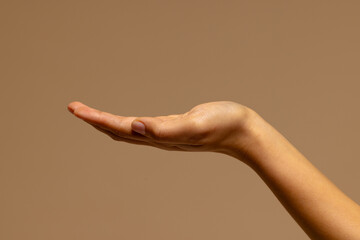 Upturned hand of biracial woman on brown background with copy space
