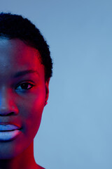 African american woman with short hair and white lipstick touching chin in red light, copy space