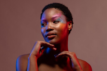 African american woman with short hair and colourful make up touching chin
