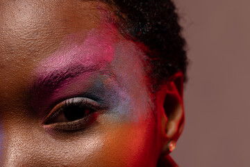 Close up of eye of african american woman with short hair and colourful make up